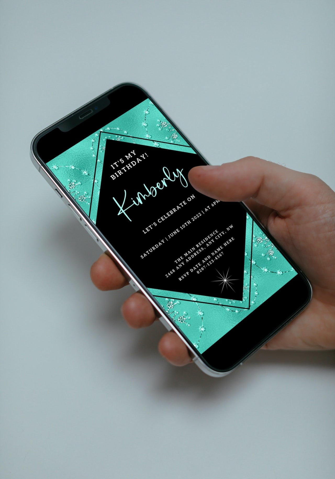 Hand holding a smartphone displaying the Teal Black Diamond Crystal Editable Birthday Evite template, customizable via Canva for digital invitations.