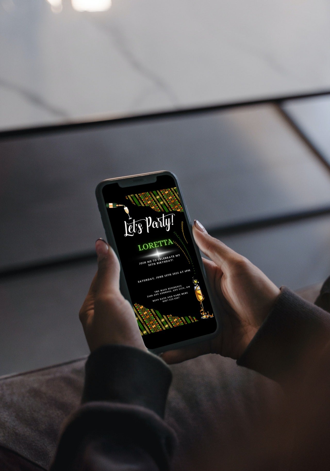 Hand holding a smartphone displaying a Green Black African Ankara Let's Party digital evite template for personalizing event invitations using Canva.