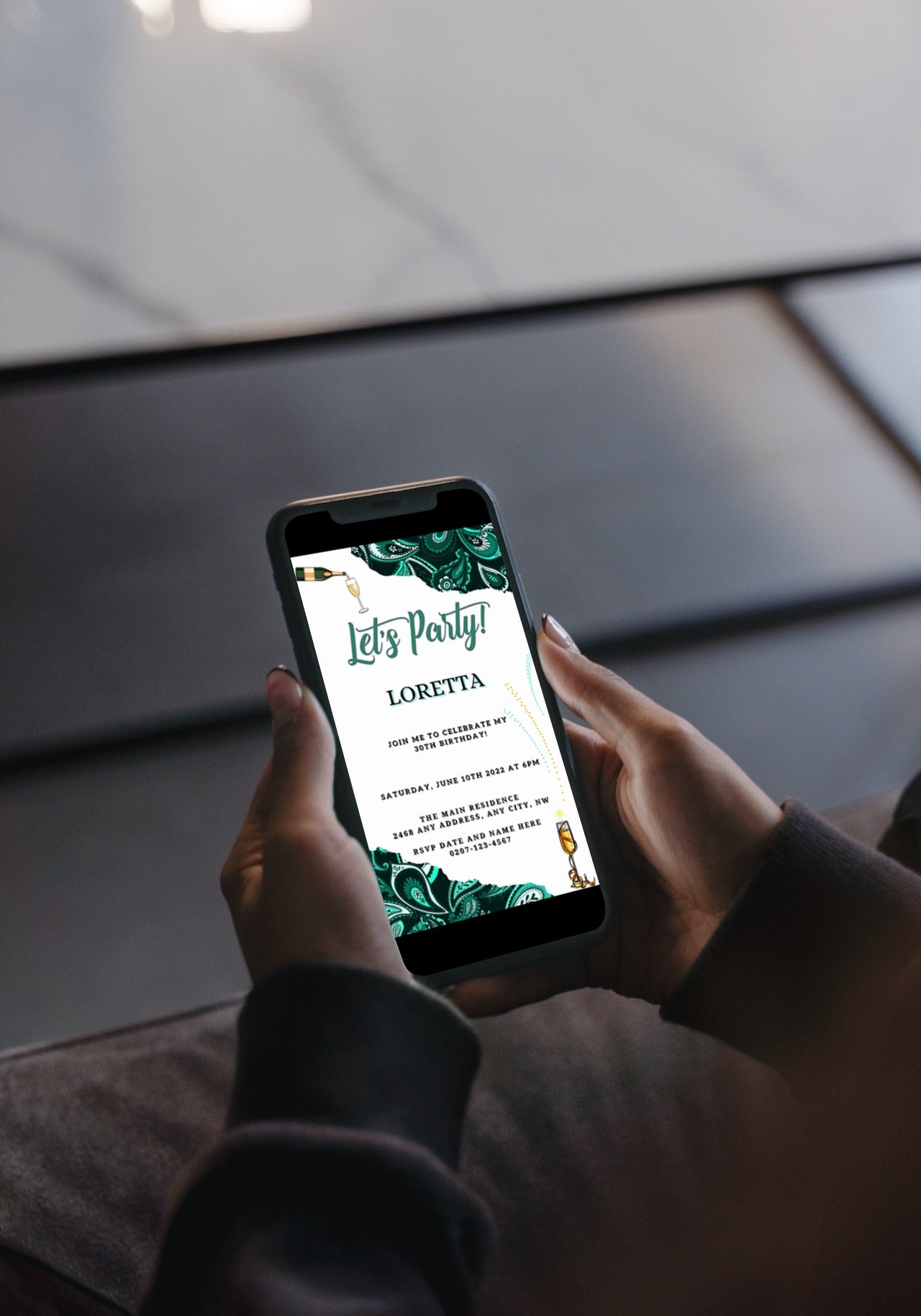 Person holding a phone displaying the African Ankara White Teal Customisable Party Evite invitation template from URCordiallyInvited.