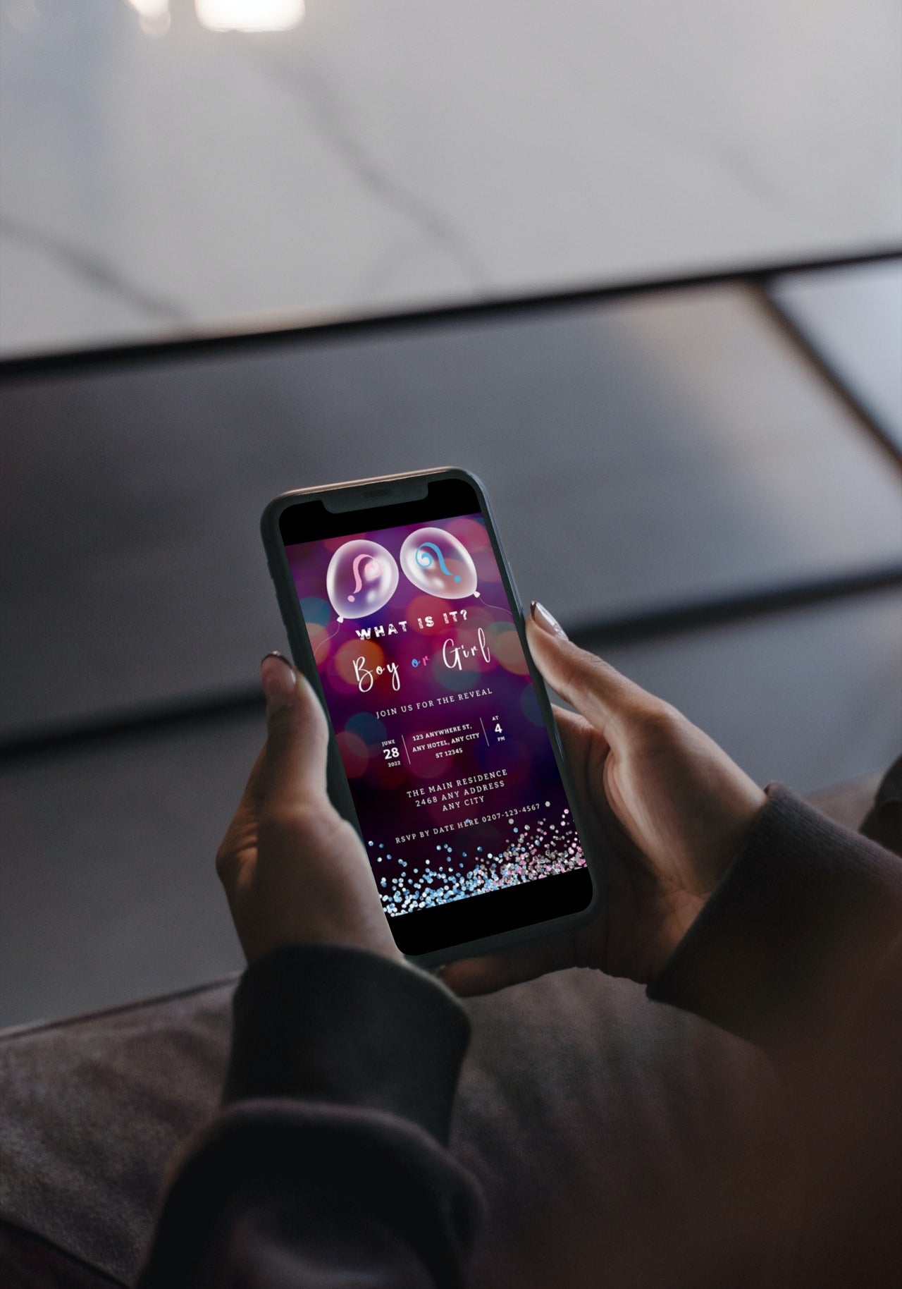 Person holding a phone displaying the Customisable Digital Balloon Pink Blue Bokeh Gender Reveal Evite, ready to be personalized and shared electronically.