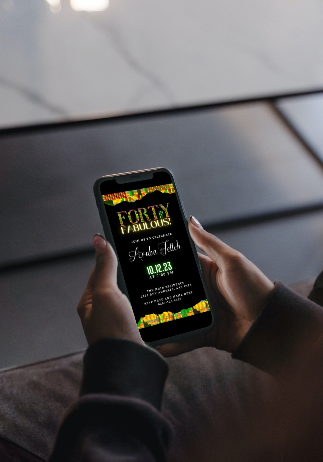 Person holding a smartphone displaying the Editable Digital Green Yellow Kente | 40 & Fabulous Party Evite template for customization via Canva.