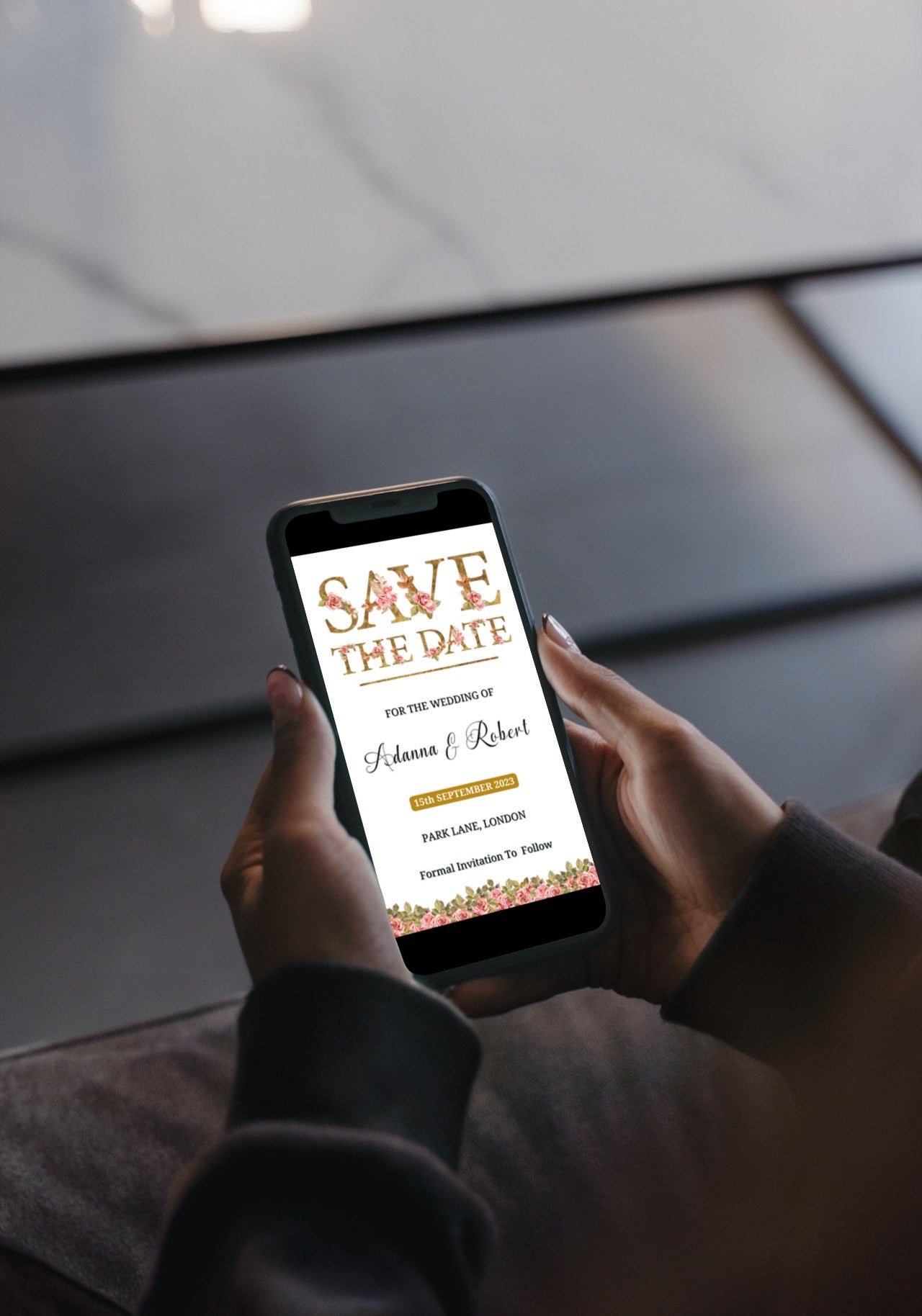 Person holding a smartphone with a Gold Pink Floral Roses Save The Date Evite template displayed on the screen.