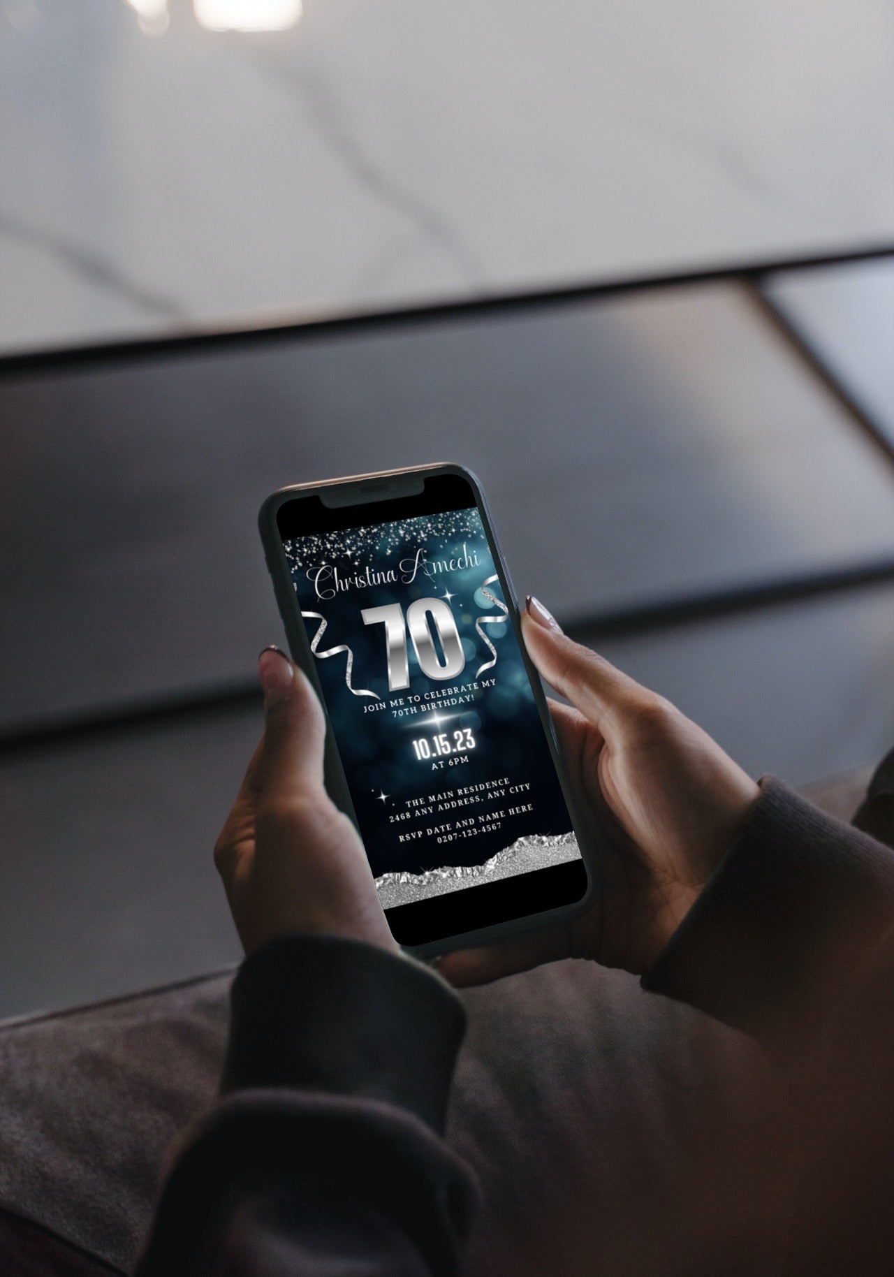 Person holding a smartphone displaying a customizable Navy Blue Silver Glitter 70th Birthday Evite template from URCordiallyInvited.