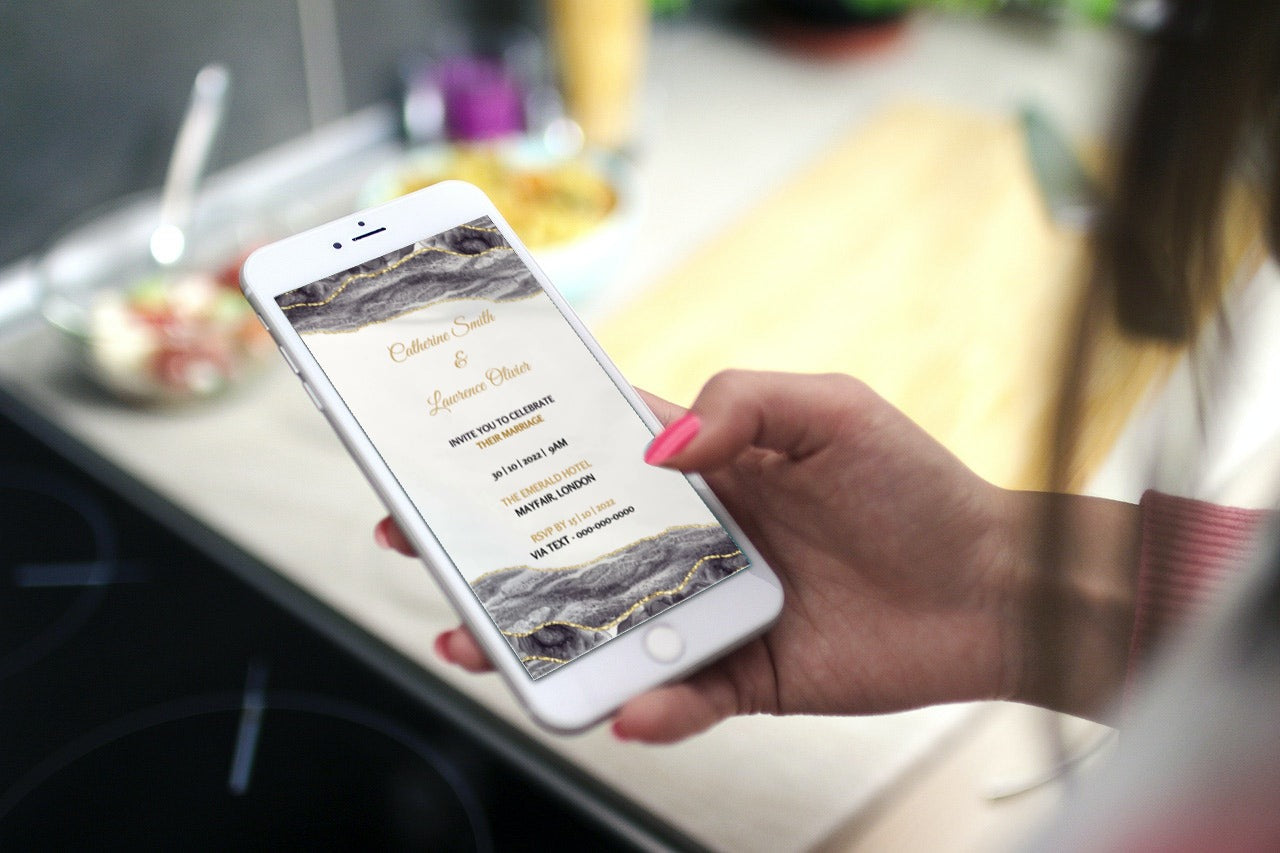 Hand holding a phone displaying a customizable Black Gold Agate Digital Wedding Video Invitation from URCordiallyInvited.