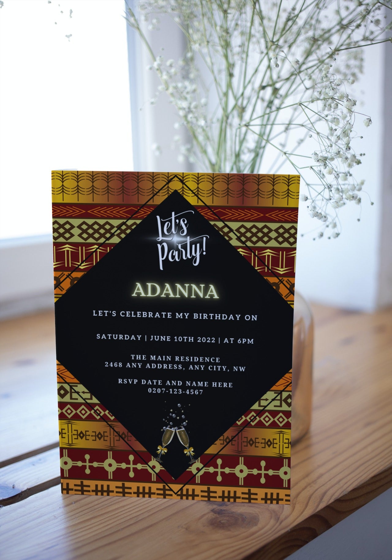 Gold Yellow African Ankara Editable Party Evite displayed on a table, showcasing customizable text and design elements for digital invitations via Canva.