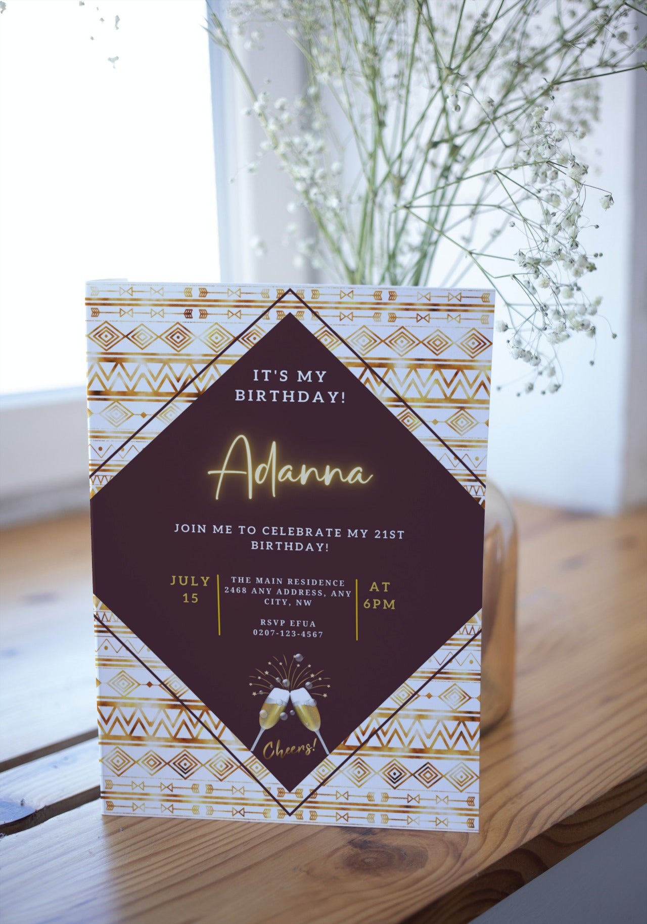 Beige White African Ankara editable party evite on a table with a card, flowers in a vase, and champagne glasses in the background.