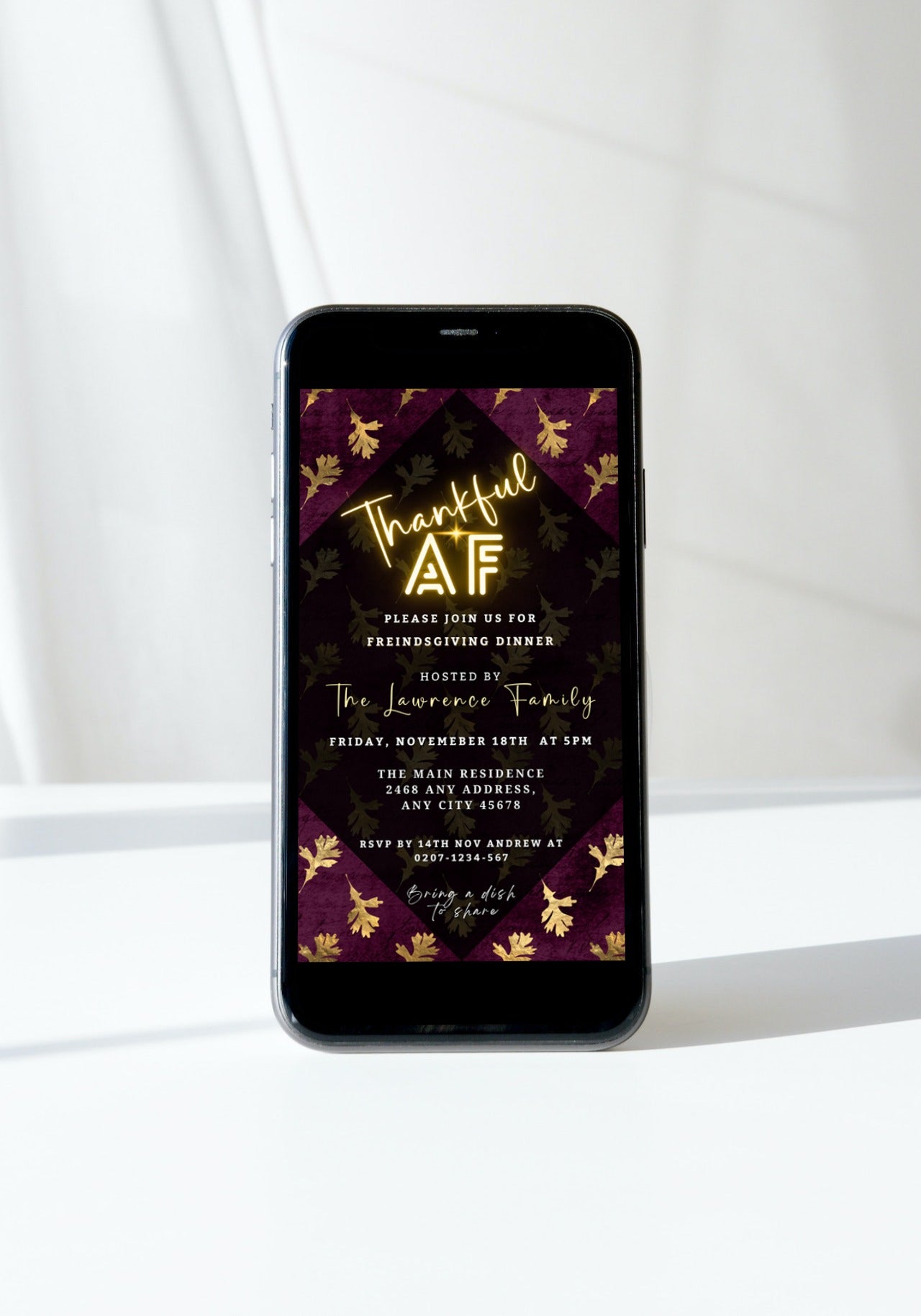 A smartphone displaying a customizable Maroon Gold Falling Leaves | Thankful AF Thanksgiving digital invitation template.