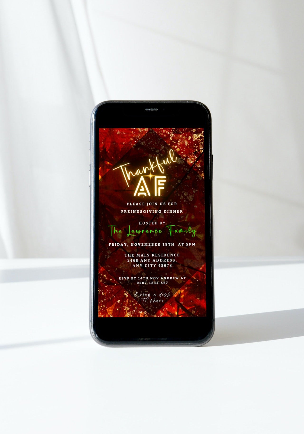 Cell phone displaying a personalized Rustic Red Gold Leafy Thankful AF Thanksgiving Evite template on screen.