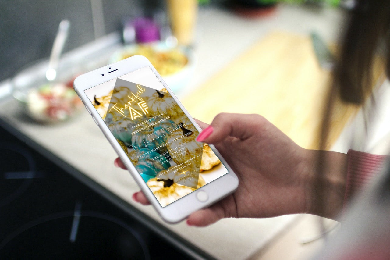 Hand holding a phone displaying the Neon Gold Teal Leaves Pumpkin | Thankful AF Thanksgiving Evite template, customizable via the Canva app for digital invitations.