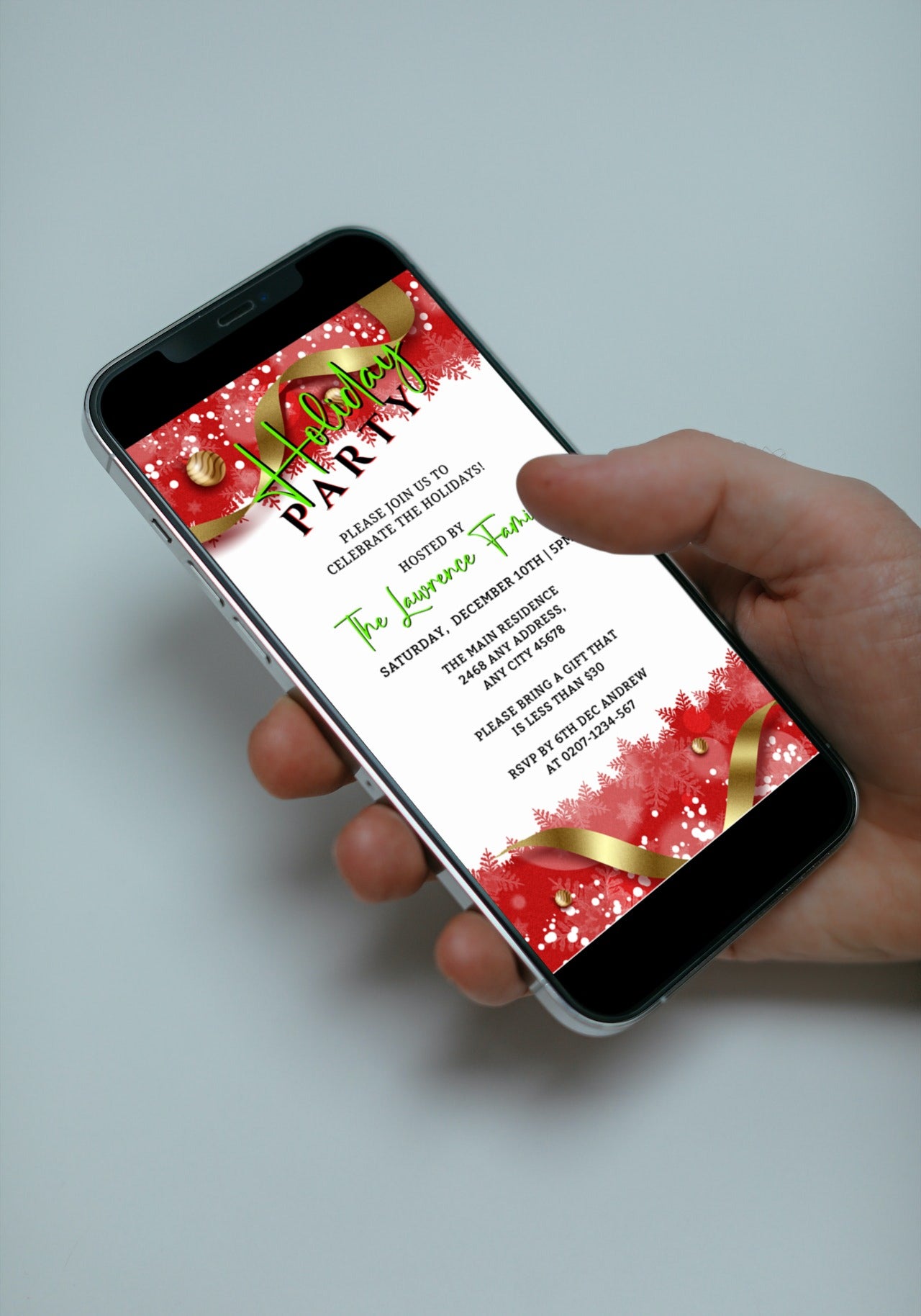 Hand holding a smartphone displaying an editable Red White Gold Ornament Holiday Party Evite template from URCordiallyInvited.
