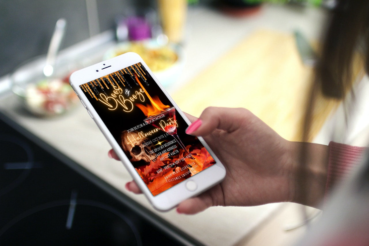Hand holding a cell phone displaying a Boos & Booze skull Flaming Eyeball Cocktail Glass Halloween Party Evite template for customization via Canva.