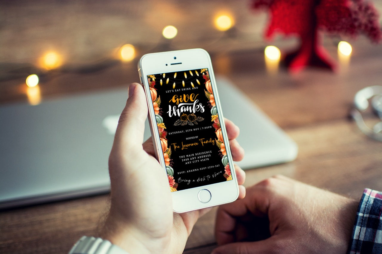 Person holding a mobile phone displaying Colourful Lit Leaves Pumpkins Black Thanksgiving Evite template, customizable with Canva for digital invitations.