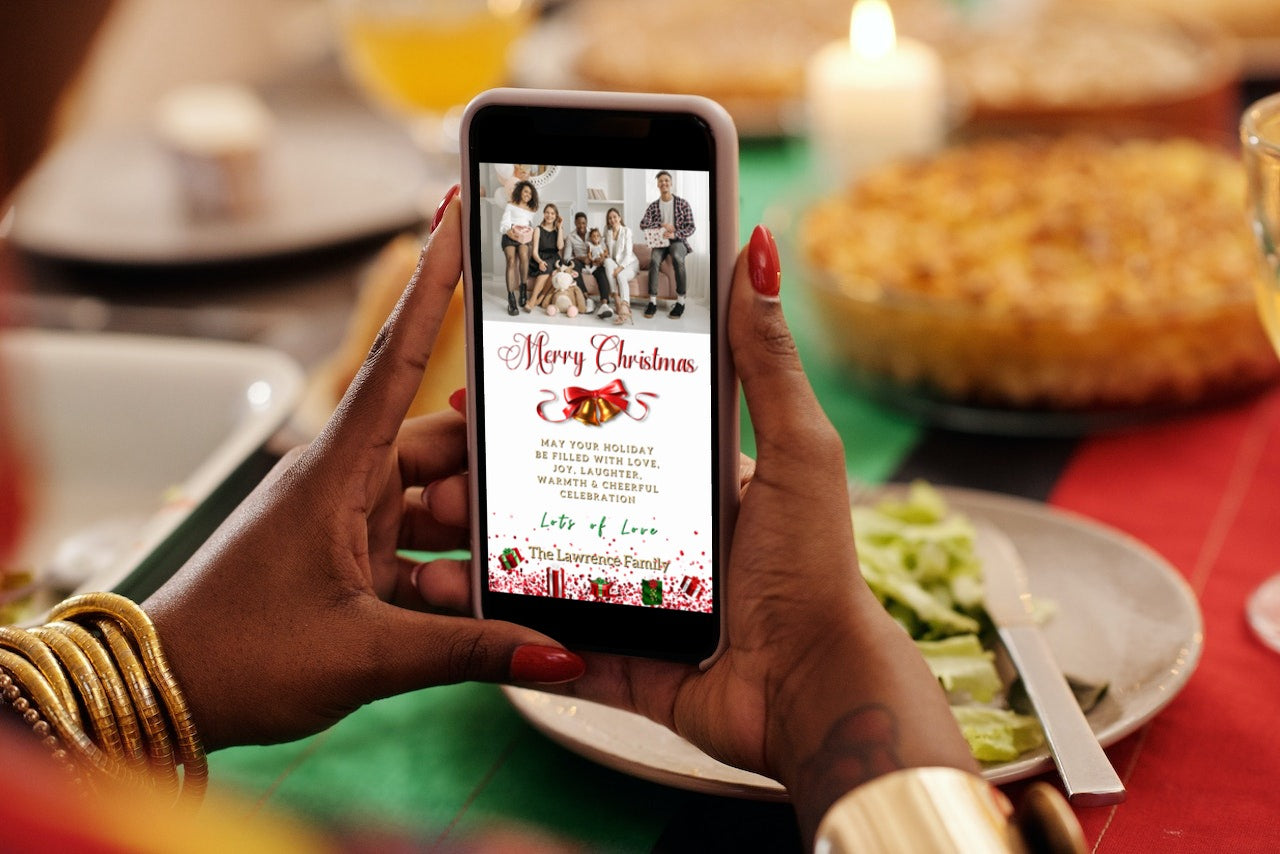 Person holding a smartphone displaying a customizable Gold Red Bell Confetti Glitter W/Photo | Merry Christmas Greeting Ecard from URCordiallyInvited.