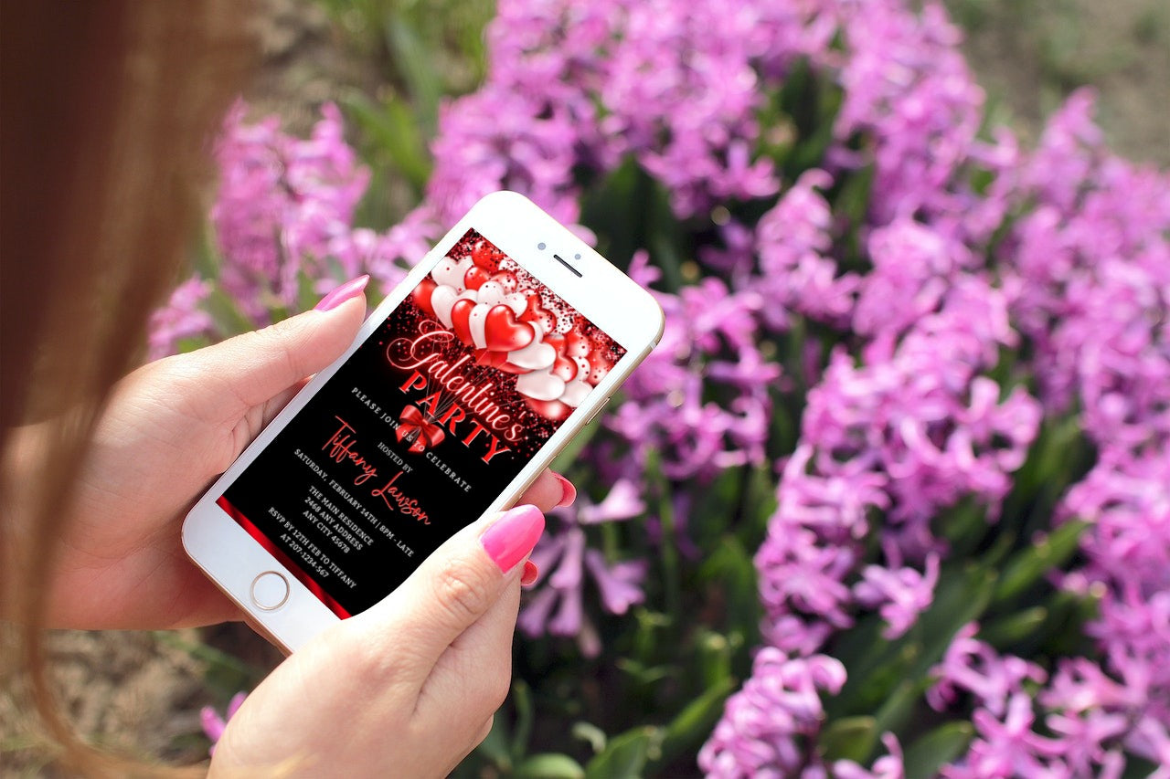 A hand holding a phone displaying a digital neon red and white balloon Galentines Party Evite template.