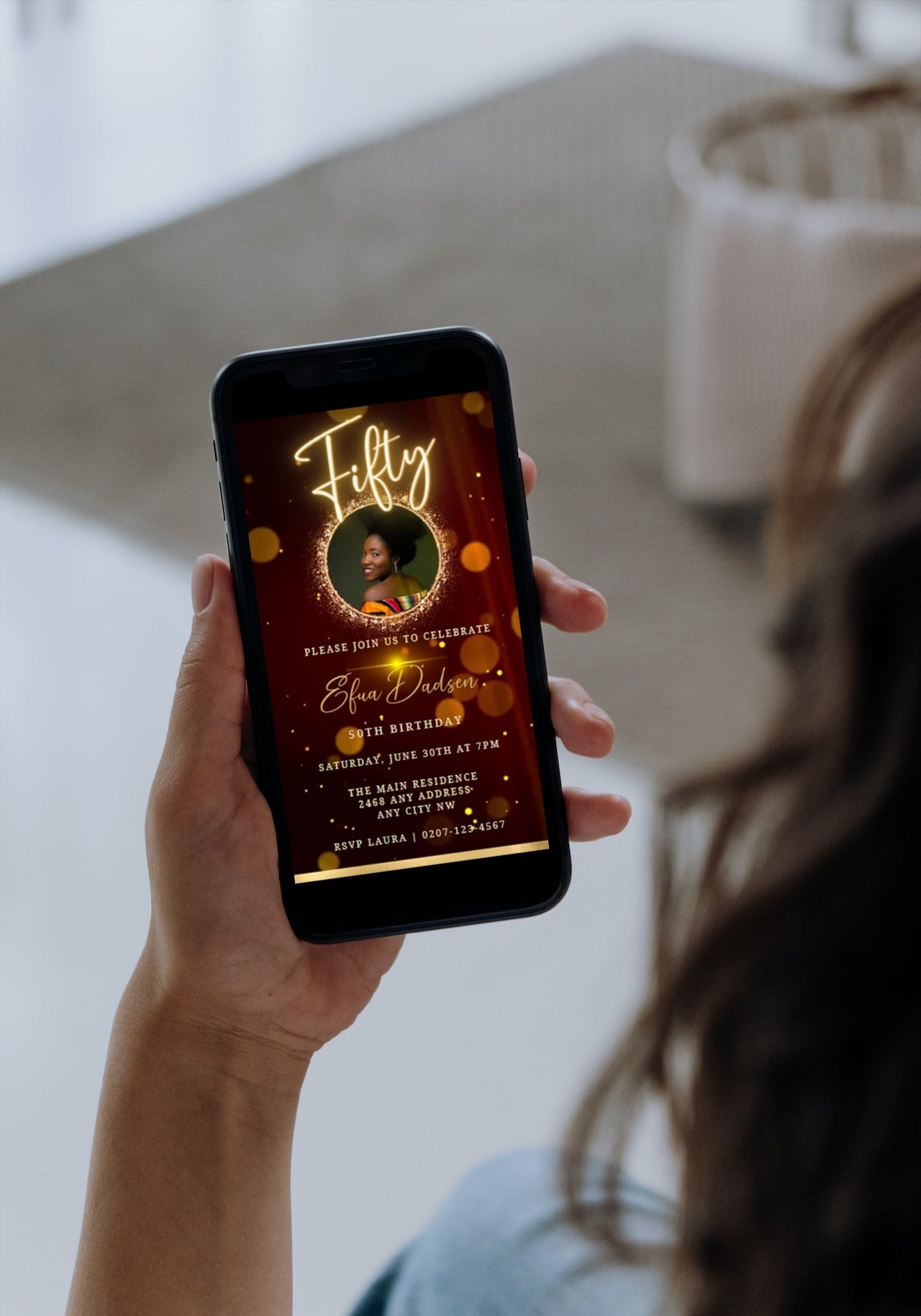 Person holding a phone displaying a customizable Digital Maroon Gold Neon 50th Birthday Video Invitation template on the screen.