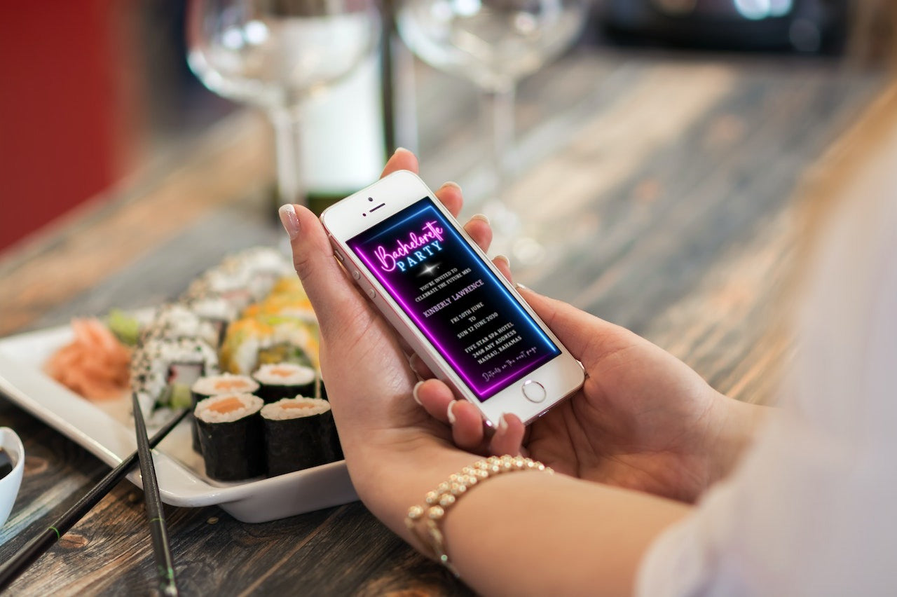 Person holding a phone displaying a customizable Neon Blue Pink Disco Bachelorette Video Invitation template.