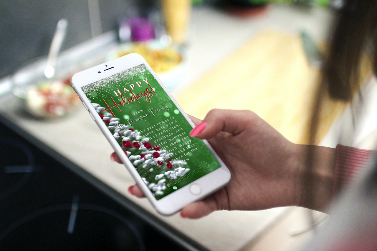 Hand holding a smartphone displaying the editable Snow Crystals Green White Christmas Video Greeting Ecard, customizable via Canva for sharing digitally.
