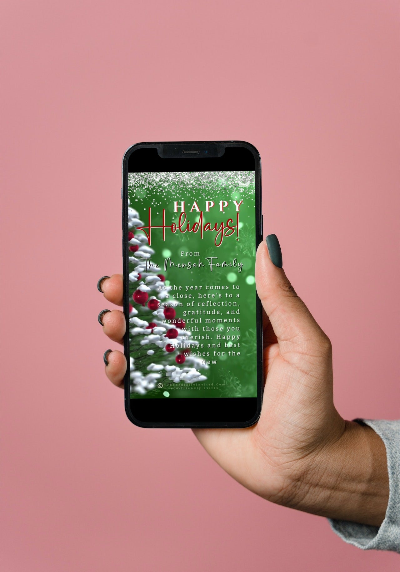 A hand holding a smartphone displaying the Snow Crystals Green White | Christmas Video Greeting Ecard template.