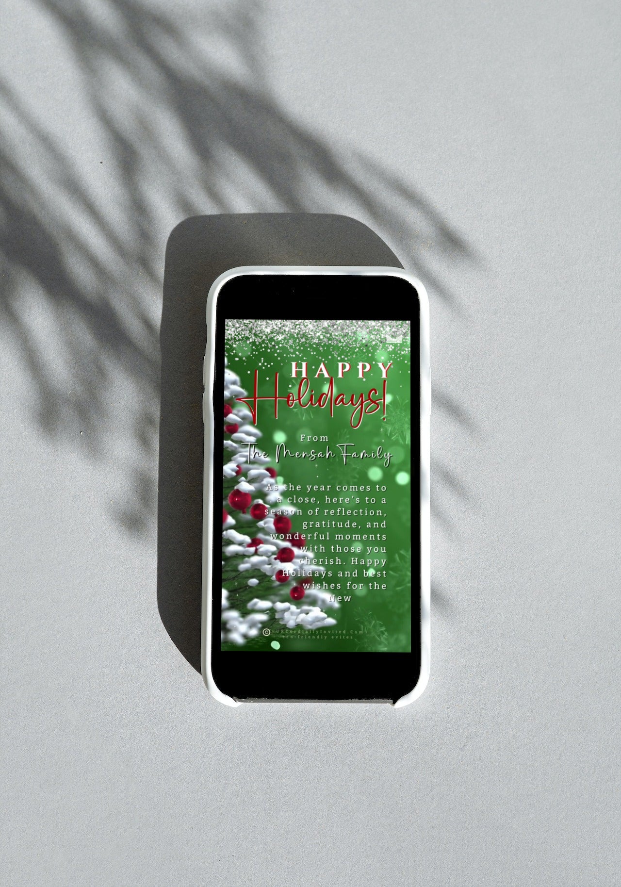 Cell phone displaying the Snow Crystals Green White | Christmas Video Greeting Ecard template with customizable text for personal events.