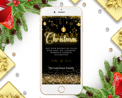 Black Gold Ornaments Glitter Merry Christmas Greeting Ecard displayed on a smartphone screen alongside a gold gift box and festive decorations.