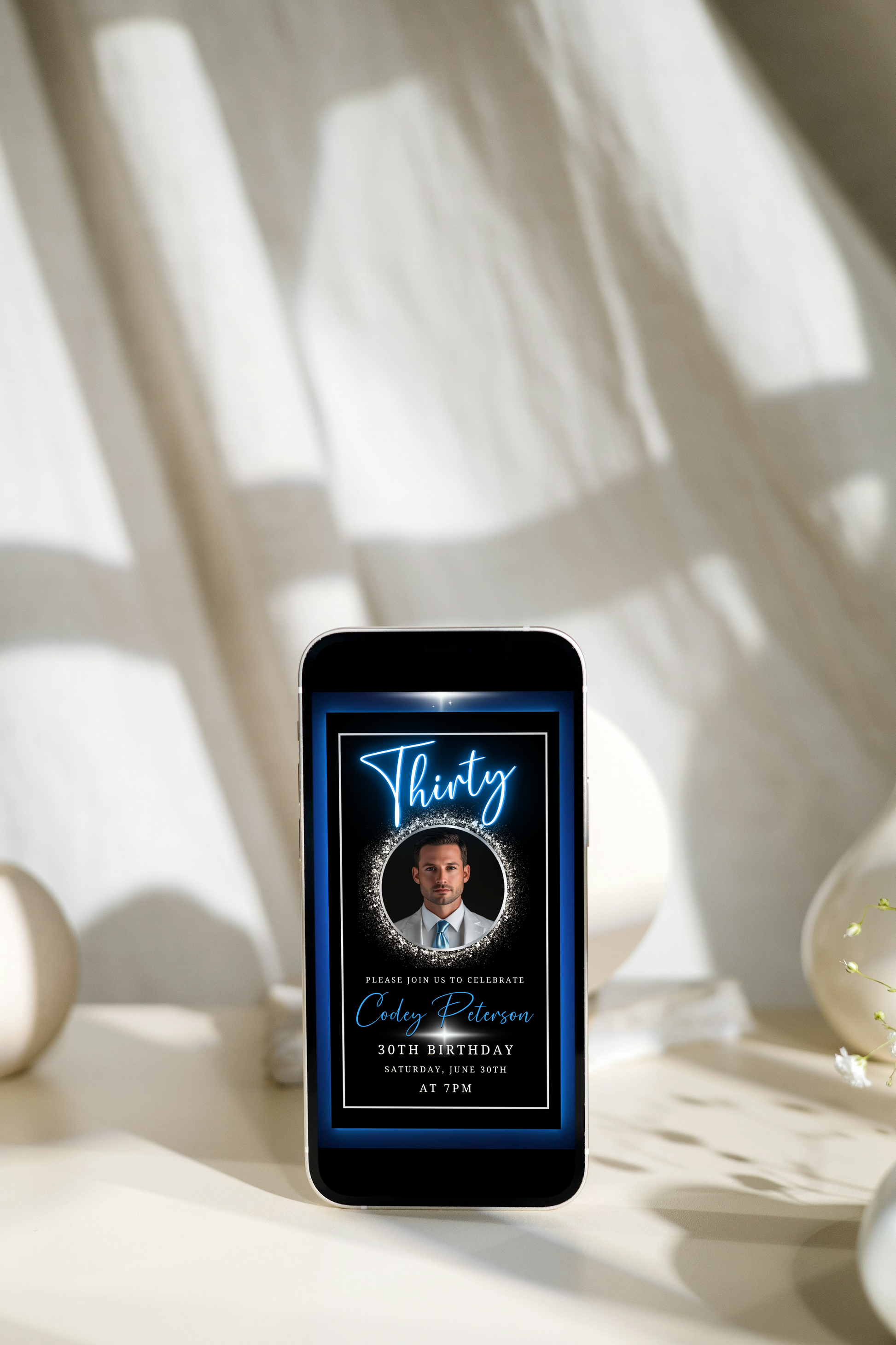 Cell phone displaying a man's image within the Blue & Silver 30th Birthday Video Invitation, featuring a sophisticated neon design for men's milestone celebrations.