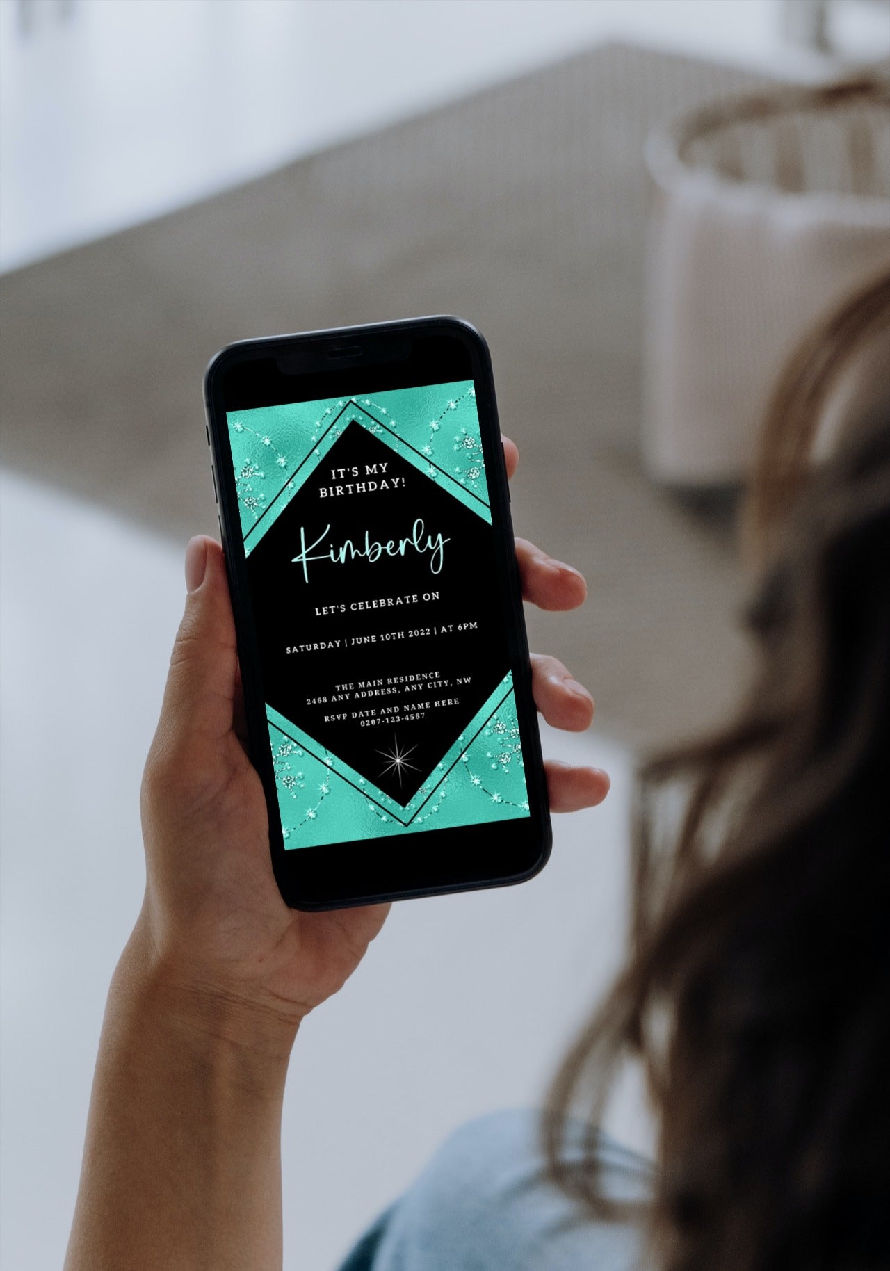 Hand holding a smartphone displaying the Teal Black Diamond Crystal Editable Birthday Evite from URCordiallyInvited.