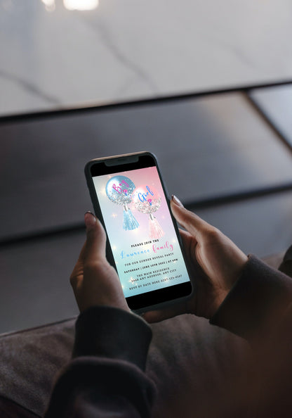 Person holding a smartphone with a customizable digital gender reveal invitation featuring blue and pink balloons and tassels displayed on the screen.