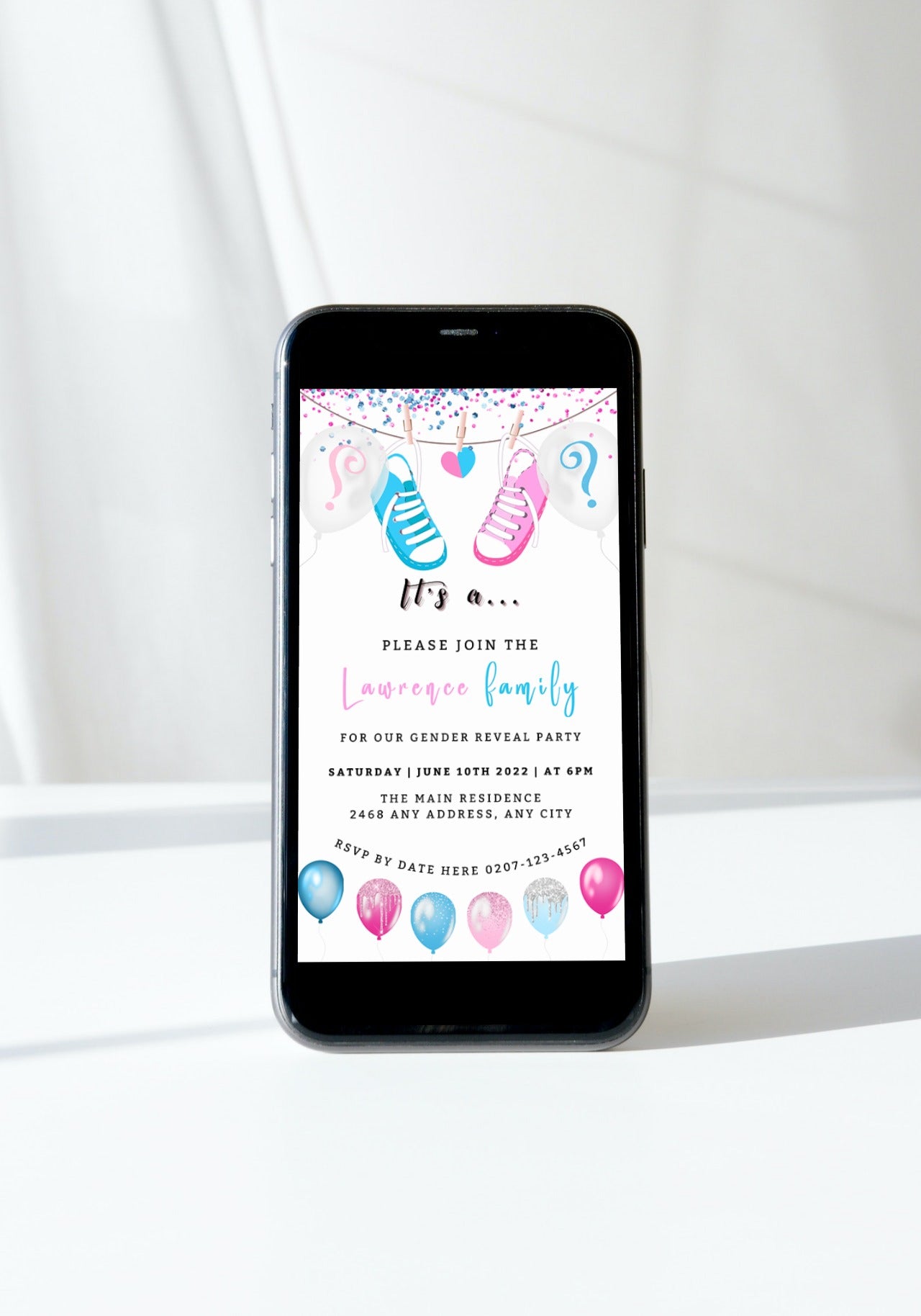 Cell phone displaying a customizable digital invitation for a baby shower with pink and blue baby shoes, designed for easy personalization via Canva.