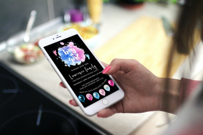 Hand holding a smartphone displaying the Customisable Digital Black Floating Pink Blue Feet Cloud Gender Reveal Evite template from URCordiallyInvited.