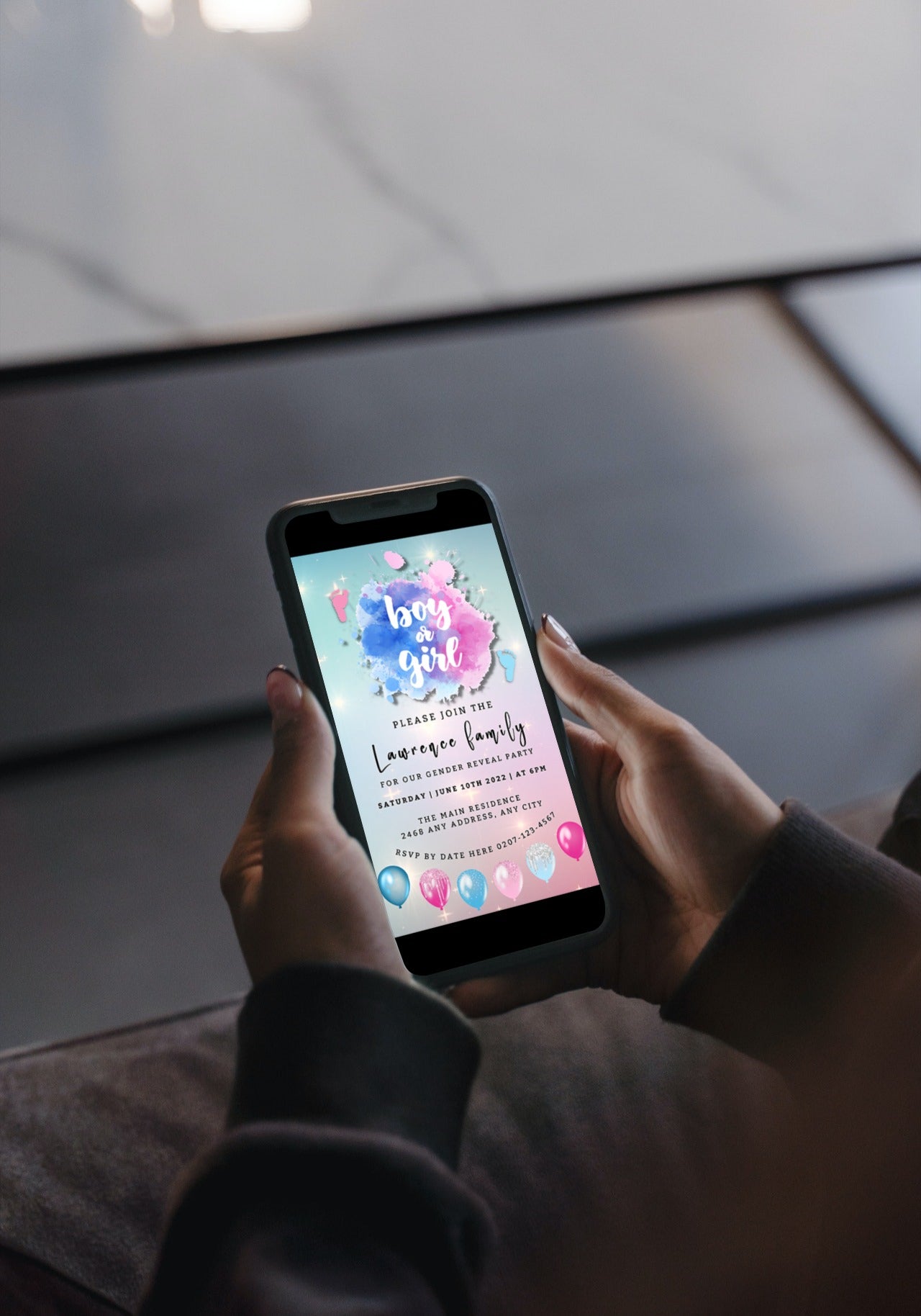 A hand holding a smartphone displaying a customizable digital Gender Reveal Evite with pink and blue sparkle feet cloud design.