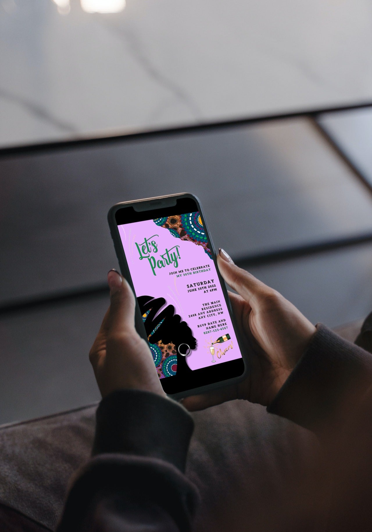 Person holding a smartphone displaying the Purple Ankara African Woman Silhouette Editable Party Evite, a customizable digital invitation template available for download and personalization via Canva.