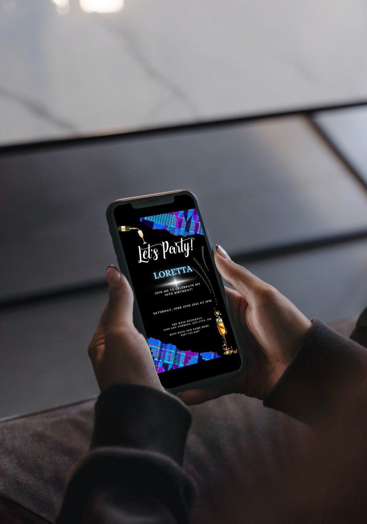 Person holding a smartphone displaying the Editable Digital Blue Purple African Kente Birthday Party Evite template, ready for customization using Canva.