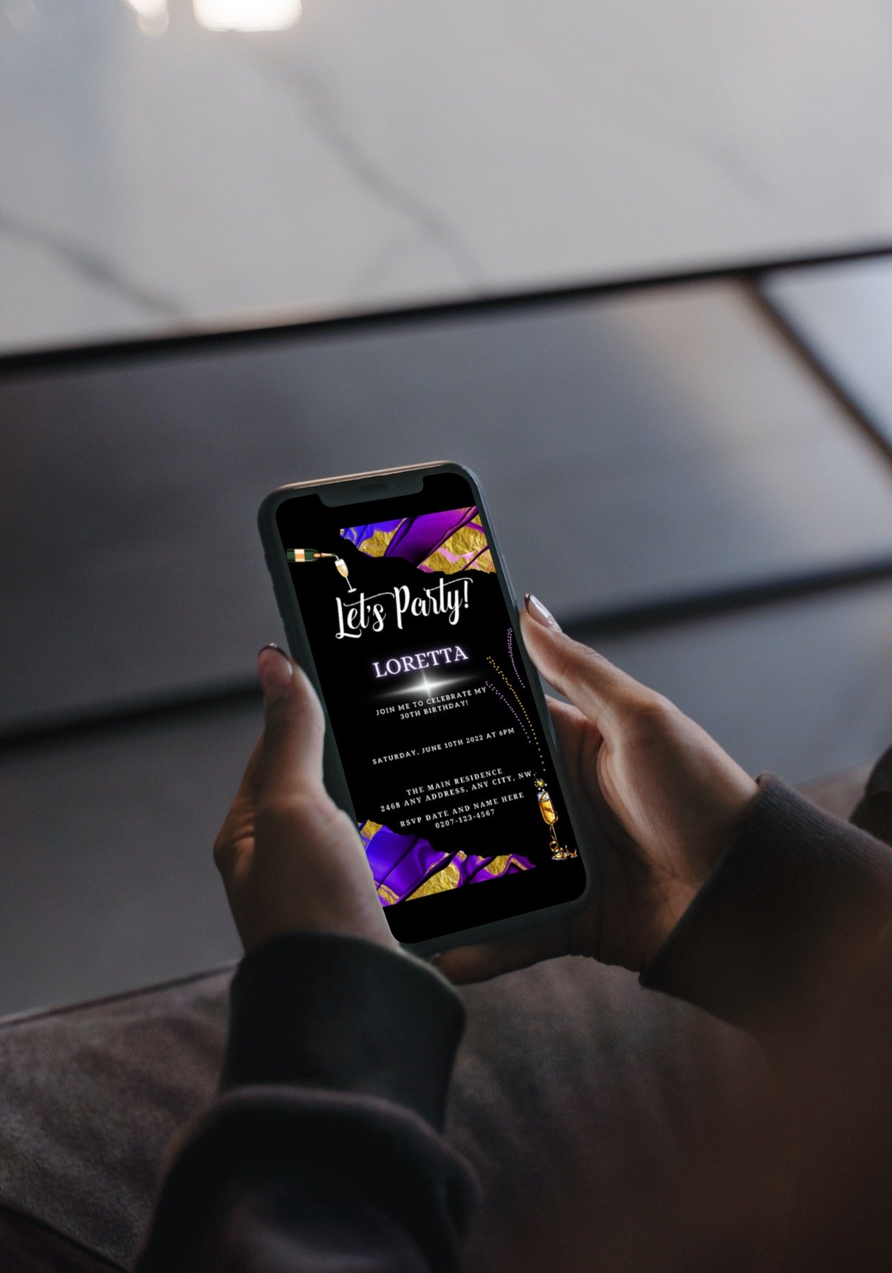 Person holding a smartphone displaying a Purple Gold Ankara Customisable Party Evite template from URCordiallyInvited.