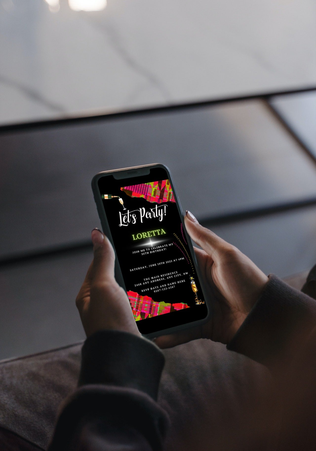 Person holding a phone displaying a customizable Pink Green African Kente party invitation template from URCordiallyInvited, designed for easy editing on Canva and digital sharing.