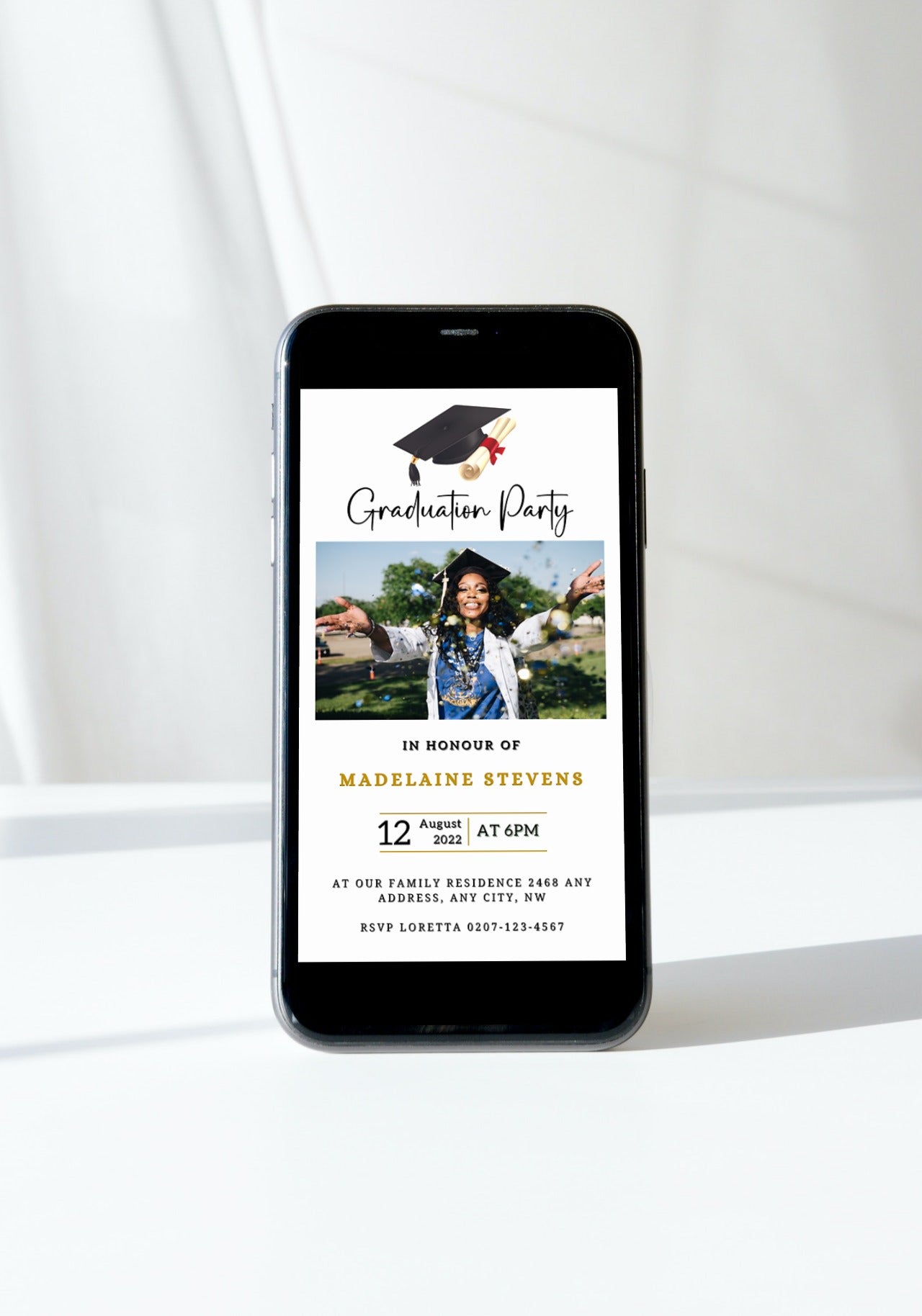 Smartphone displaying the White & Gold Graduation Invitation - With Photo Design, featuring a confetti and cap theme, perfect for customizable digital graduation announcements.