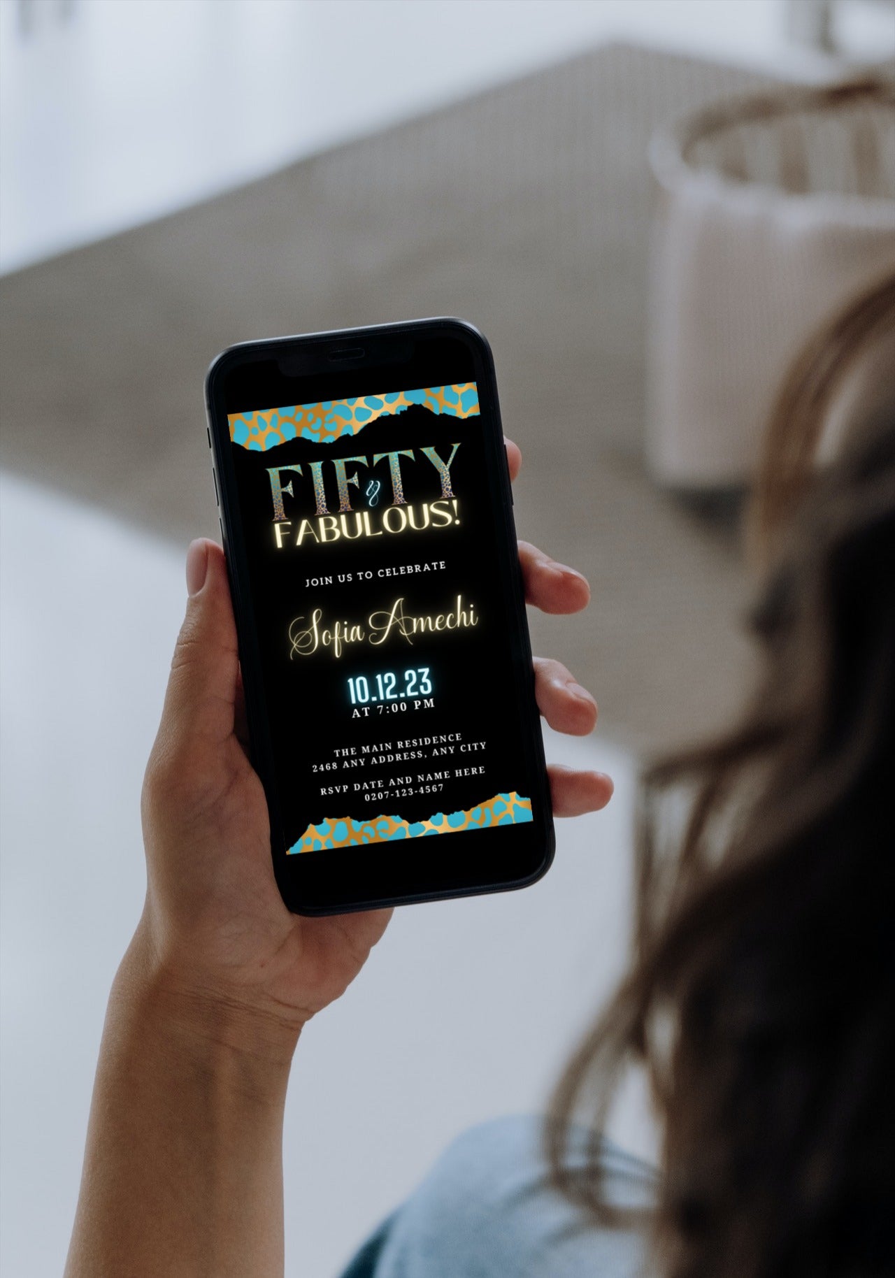 Person holding a smartphone displaying a customisable Teal Gold Cheetah Leopard | 50 & Fabulous Party Evite from URCordiallyInvited.