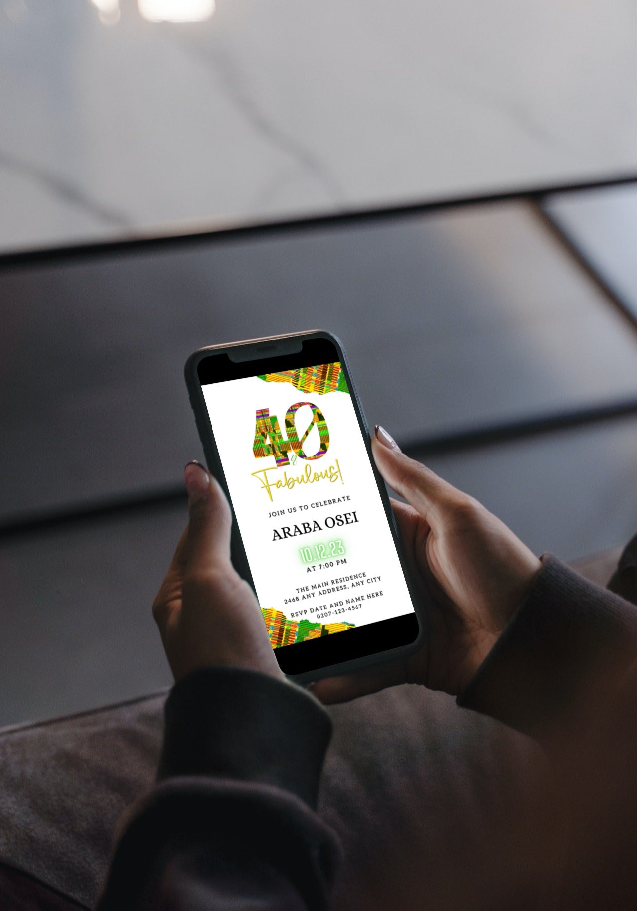 Person holding a smartphone displaying the Editable Digital White Green Yellow Kente | 40 & Fabulous Party Evite template from URCordiallyInvited.