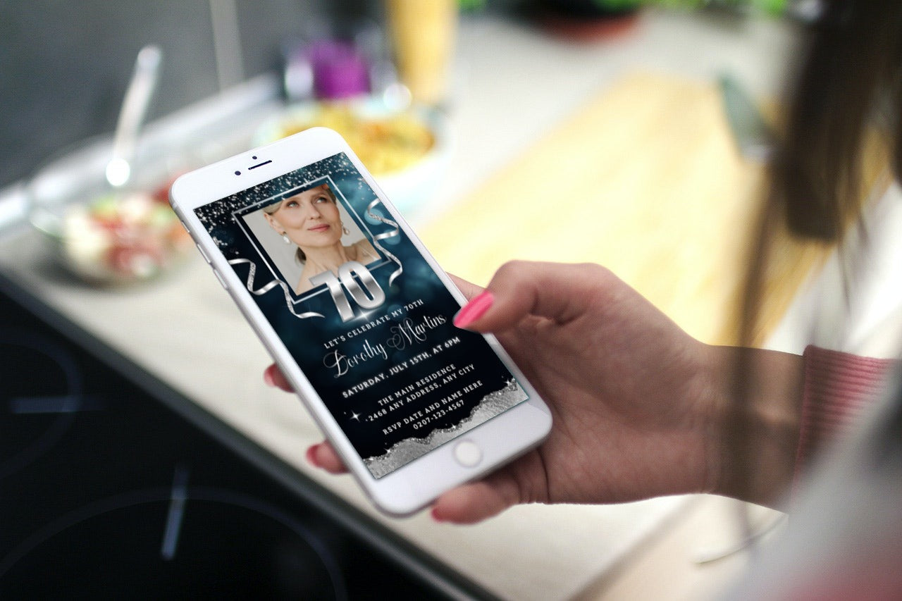 Hand holding a smartphone displaying a customisable Navy Blue Silver Glitter 70th Birthday Evite template from URCordiallyInvited.