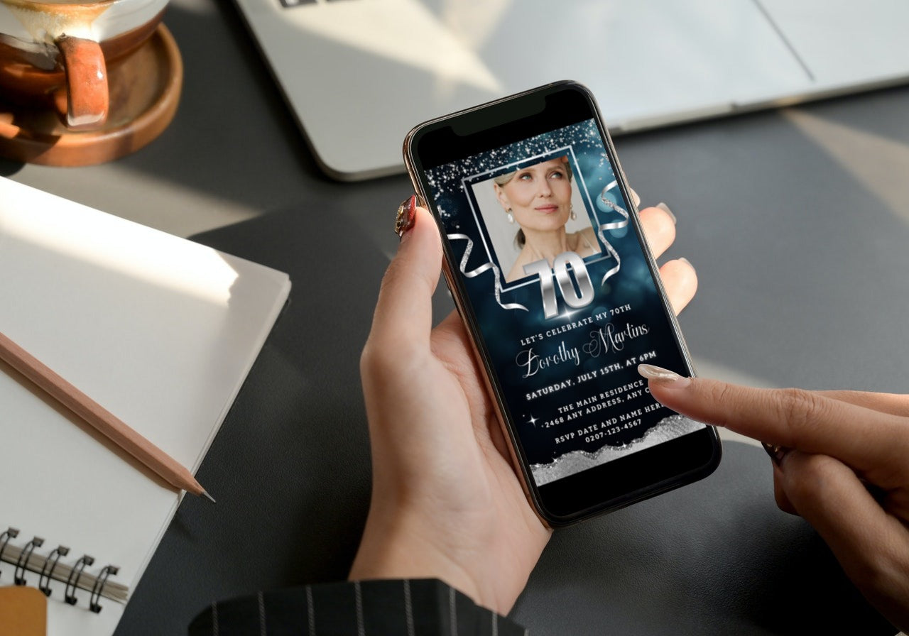 Hand holding a phone displaying a customizable Navy Blue Silver Glitter 70th Birthday Evite with a photo, ready for personalizing via Canva.