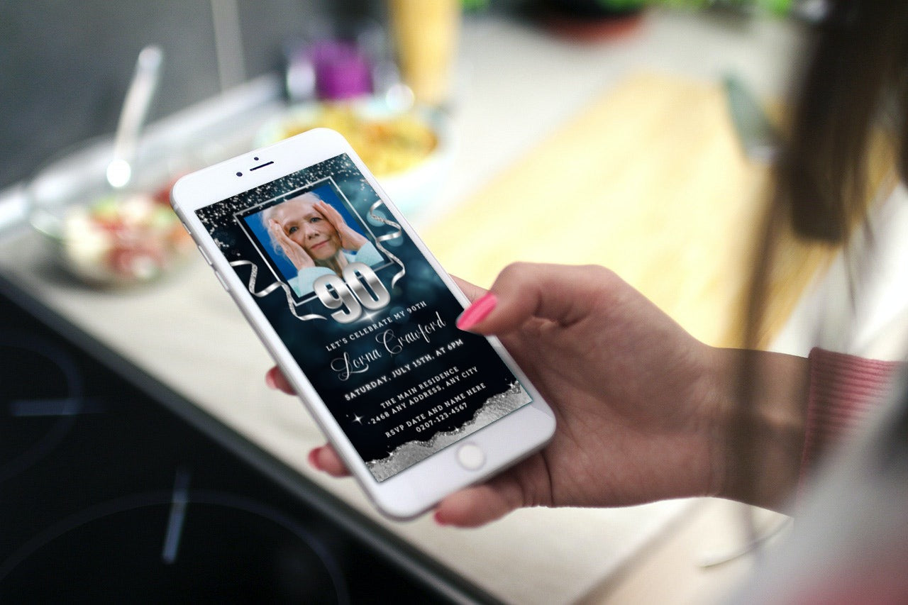 A hand holding a smartphone displaying a customisable Digital Navy Blue Silver Glitter 90th Birthday Evite with editable text and photo.