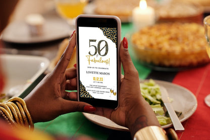 Person holding a smartphone displaying the customizable Digital Blue Gold Leopard | 50 & Fabulous Party Evite template from URCordiallyInvited.