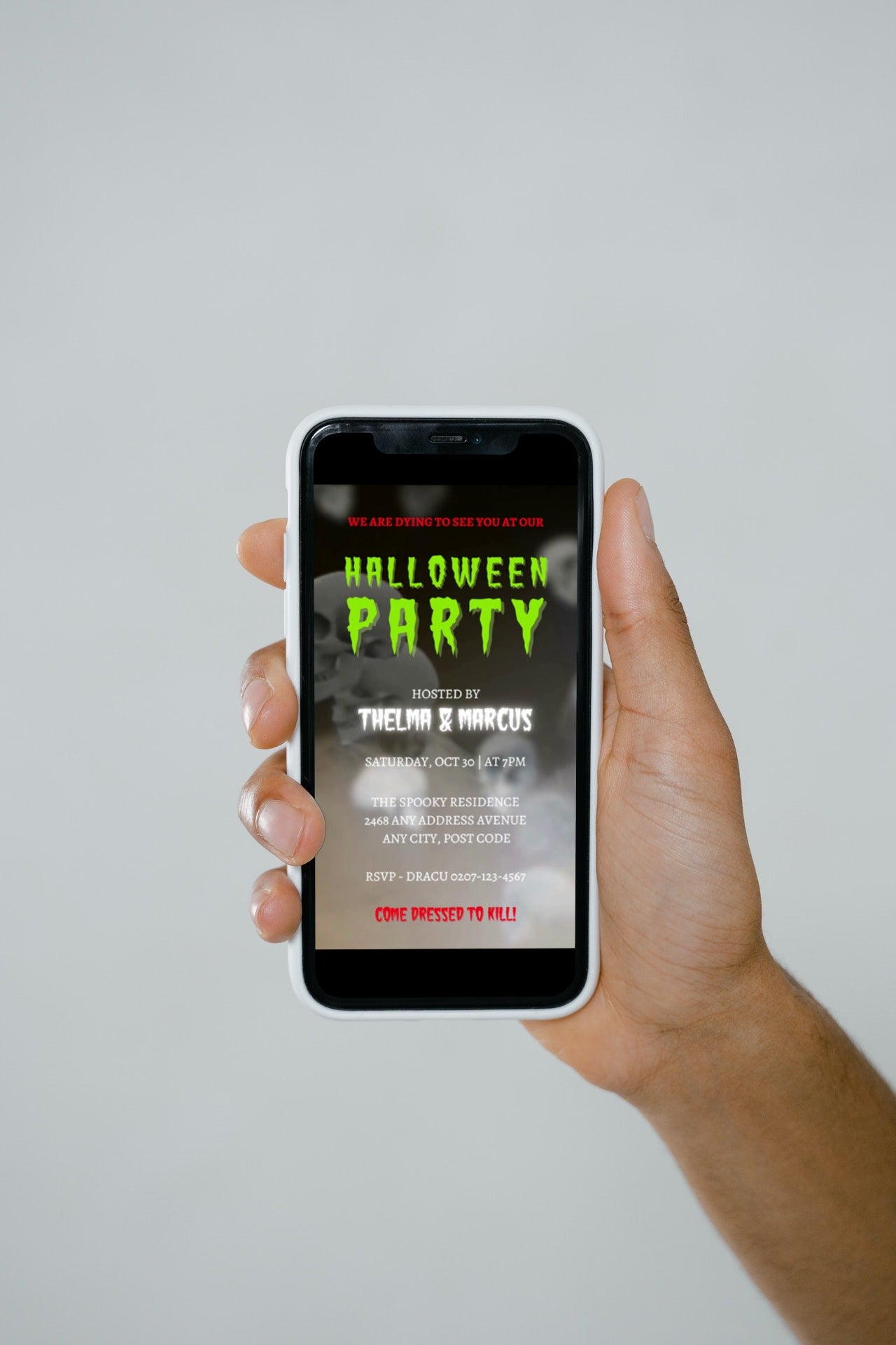 A hand holding a phone displaying a Spinning Smoking Skulls | Halloween Party Video Invite.