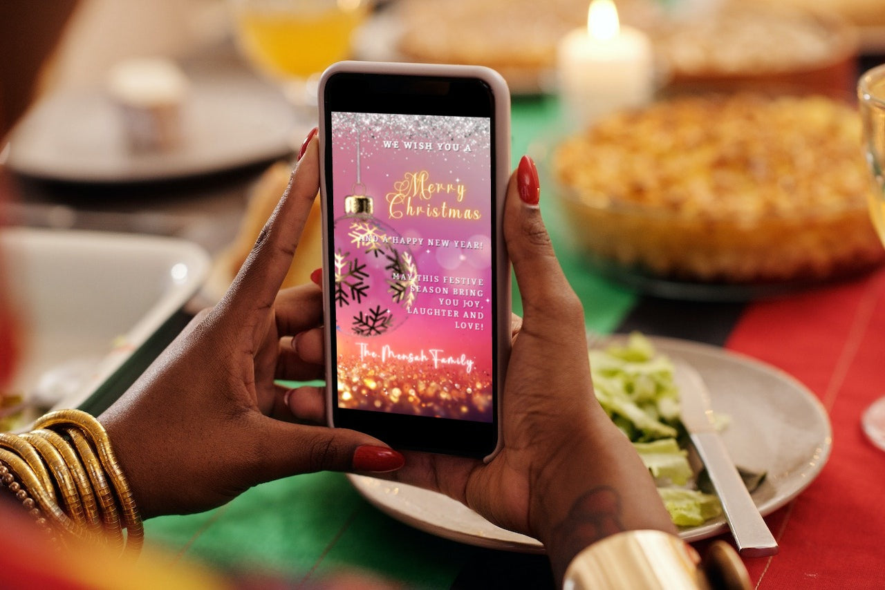 A person holding a smartphone displaying the Fuchsia Gold Ball Glitter Christmas Video Ecard template from URCordiallyInvited.