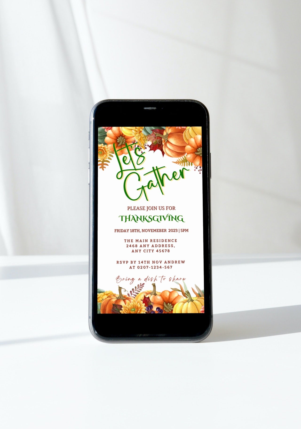 Cell phone displaying Colourful Pumpkins Let's Gather | Thanksgiving Evite template with pumpkins and flowers in the background.