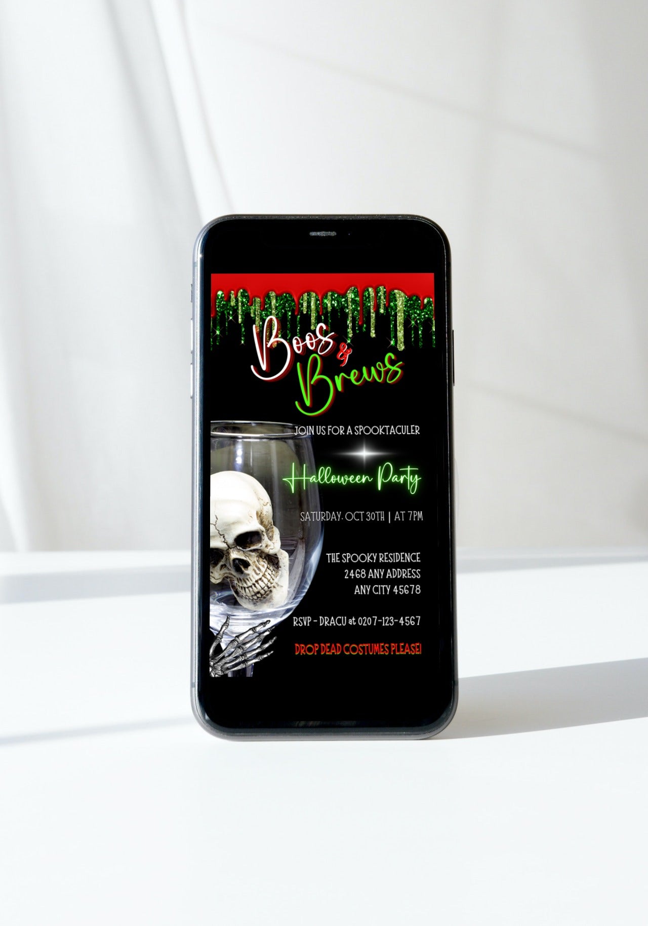 Cell phone displaying a Halloween-themed invitation with a skull in a glass, titled Boos & Brews Glass Skull | Halloween Evite.