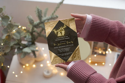 Person holding a black and gold Gold Pumpkin Glitter Foil | Thankful AF Thanksgiving Evite card, customizable via Canva.