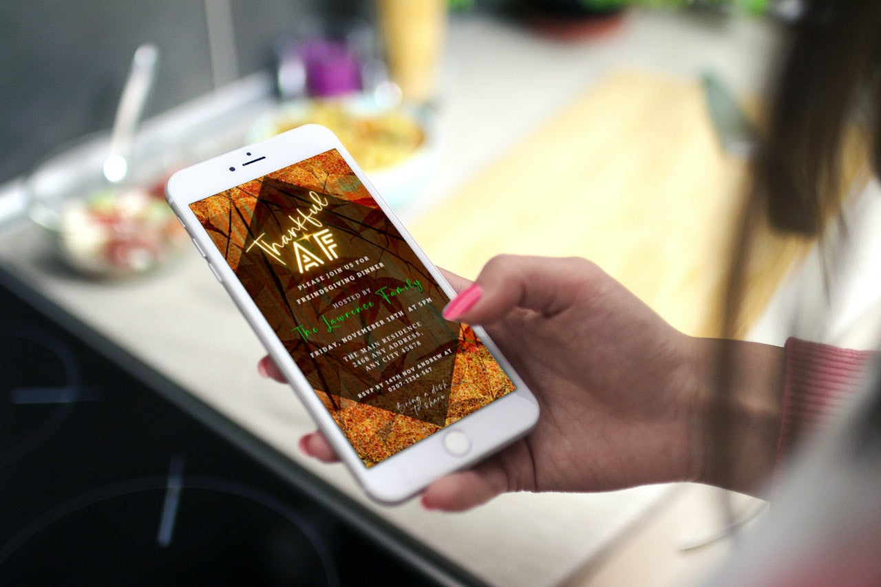 Hand holding a smartphone displaying the Thankful AF Orange Gold Pumpkin Background | Thanksgiving Dinner Evite. Editable and printable digital invitation template available for customization via Canva.