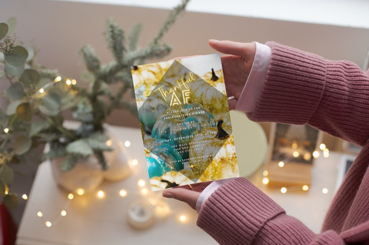 A person holding a customizable Thanksgiving Evite card titled Neon Gold Teal Leaves Pumpkin | Thankful AF Thanksgiving Evite.