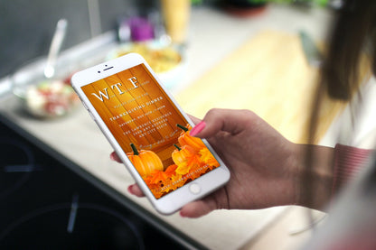 Hand holding a phone displaying a personalized Yellow Wood Pumpkin Leaves Thanksgiving Evite template from URCordiallyInvited.