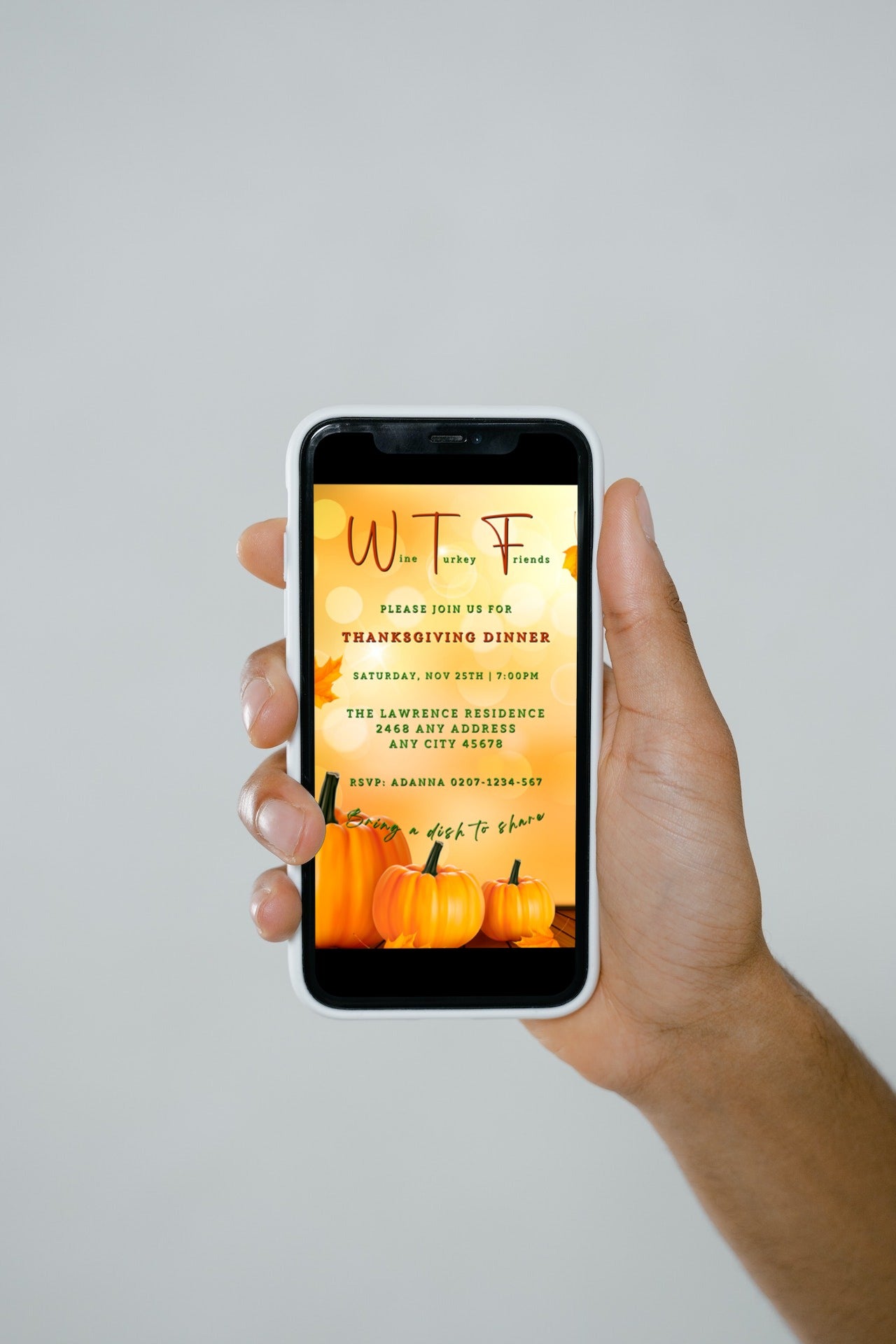 Hand holding a smartphone displaying the Golden Bokeh Pumpkin| WTF Thanksgiving Evite template, customizable via the Canva app for digital invitations.